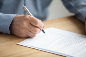 Person with a pen signing a paper application