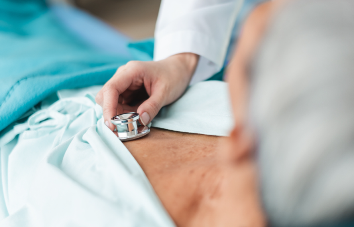 A man getting his lungs and breathing checked by a medical professional with a stethoscope