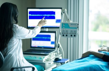 Medical professional reading data from a screen next to a patient receiving treatment